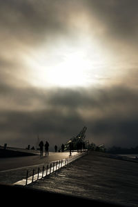 View of pier on beach against cloudy sky