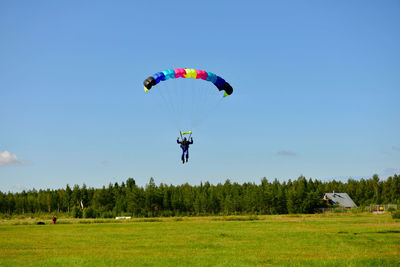 People skydiving on field against clear sky