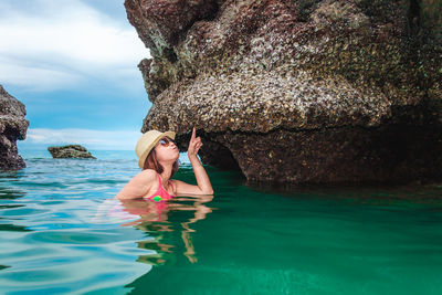 Woman standing on rock by sea