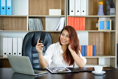 Young woman using phone while sitting on table