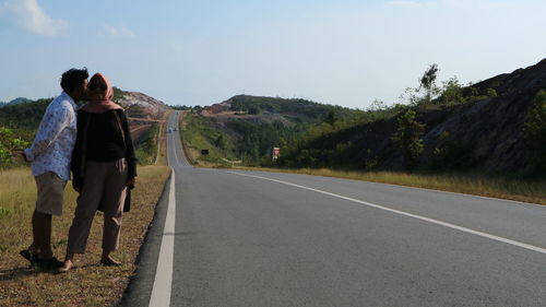 Man kissing woman while standing on roadside