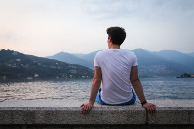 Rear view of man standing on lake against sky