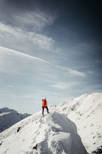 Rear view of man walking on snow covered mountain against sky