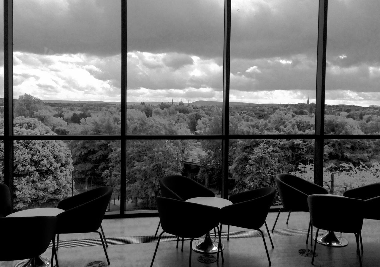 CHAIRS AND TABLE AGAINST SKY SEEN FROM WINDOW