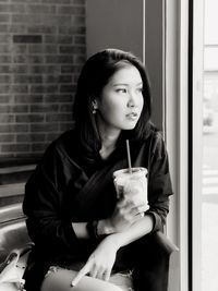 Young woman looking away while sitting on table