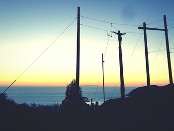 Silhouette trees by sea against sky during sunset