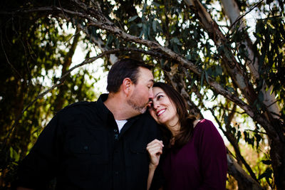 Young couple smiling against trees