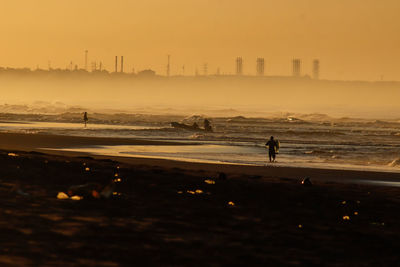 Silhouette fisherman at beach at dawn