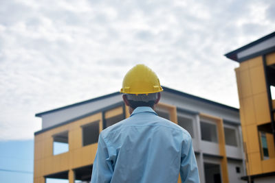 Rear view of man working against sky