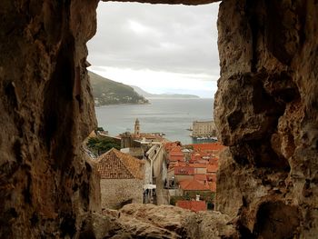 Townscape by sea seen from cave against sky