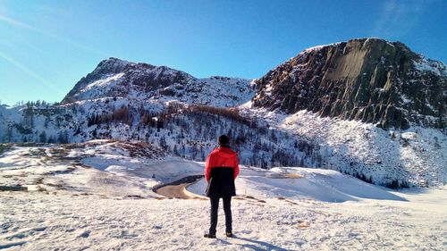 Rear view of man standing on snow covered mountain