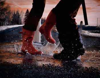 Low section of people splashing puddle on road