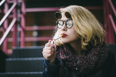 Close-up of woman igniting cigarette while sitting on staircase