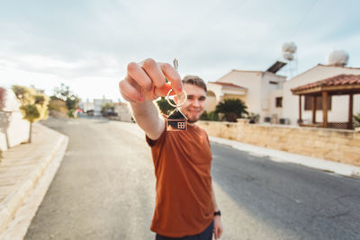 Man holding umbrella standing on road against sky