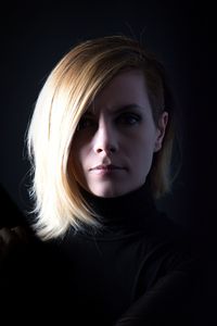 Portrait of beautiful young woman against black background