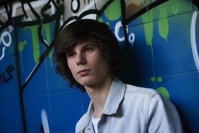 Close-up of thoughtful young man looking away against wall