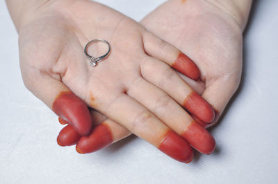 Cropped hands of bride holding wedding ring on white table