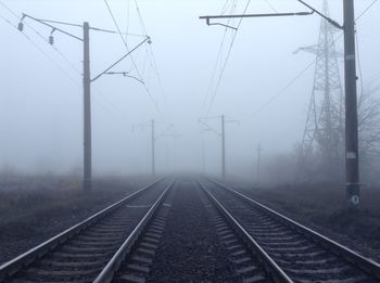 Railroad tracks against sky during foggy weather