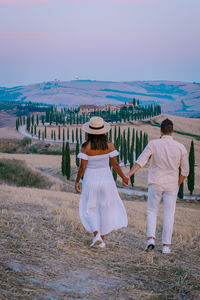 Rear view of couple walking on field