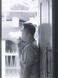 Side view of man smoking cigarette at doorway