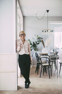 Portrait of woman holding coffee cup at home