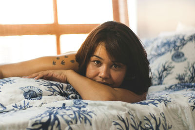 Portrait of smiling woman lying on bed at home