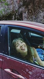 Portrait of young woman sticking out tongue in car