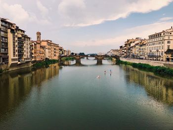 Bridge over river amidst buildings in city against sky