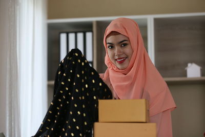 Portrait of smiling young woman holding box