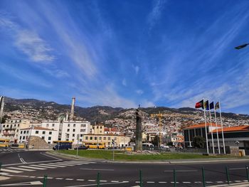 Road by buildings against blue sky