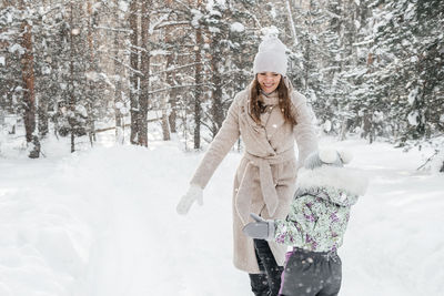 Mother and daughter have fun running in the snowy forest. high quality photo