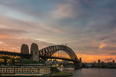 View of bridge over river and buildings against cloudy sky