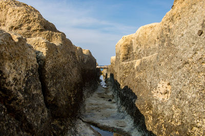 Footpath amidst rocks against sky