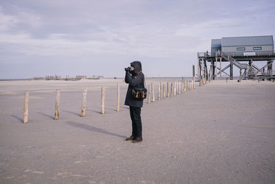 Rear view of man standing on beach against sky