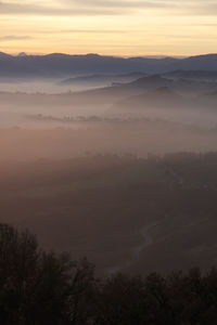 Scenic view of landscape with road against foggy valley and sky during morning