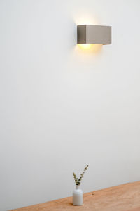 Electric lamp on table against white wall at home