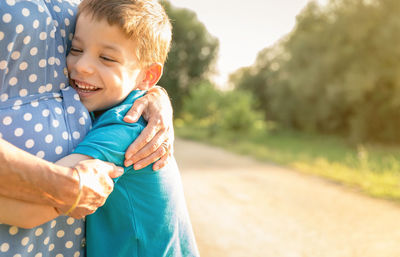 Midsection of grandmother embracing grandson at park