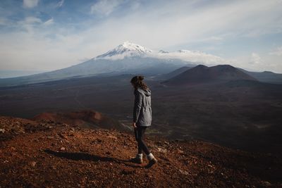 Rear view of man standing on mountain against sky