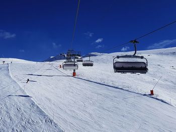 Ski lift over snowcapped mountains against sky