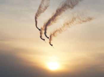 Low angle view of airplane flying against sky during sunset