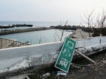 Information sign by sea against clear sky