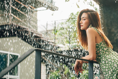 Young woman looking down while standing on railing