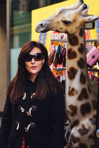 Woman wearing sunglasses while standing by giraffe sculpture