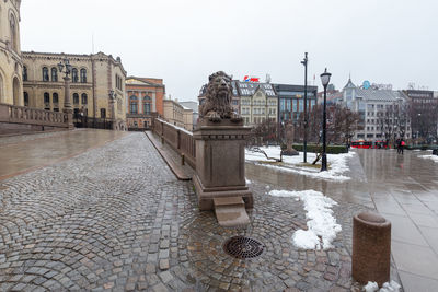 Statue by street against buildings in city