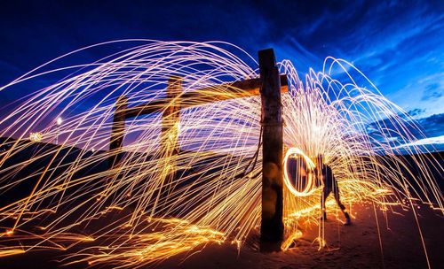 Person spinning wire wool by wooden structure at beach