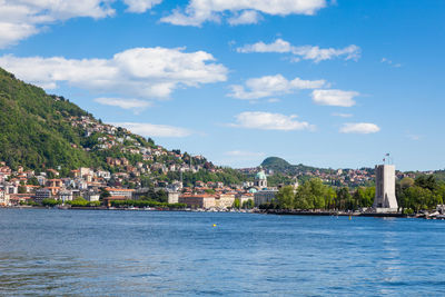 Buildings at waterfront against cloudy sky