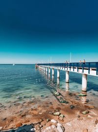 Pier over sea against clear blue sky