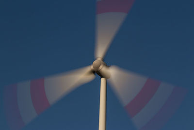 Low angle view of wind turbine against blue sky