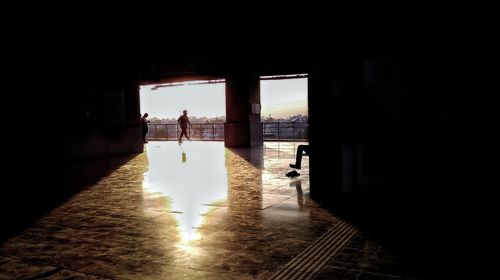 Silhouette building by sea seen through window