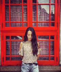 Portrait of beautiful young woman standing against red brick wall